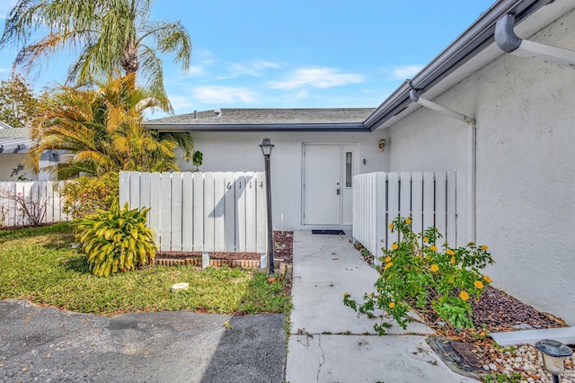 doorway to property featuring stucco siding and fence