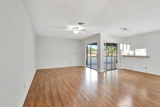 unfurnished room with a ceiling fan, wood finished floors, baseboards, and visible vents