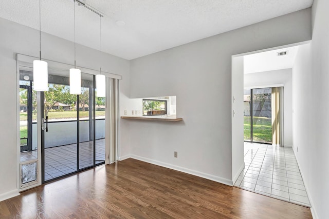 empty room with a textured ceiling, visible vents, and wood finished floors
