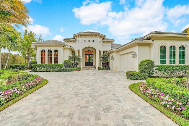 mediterranean / spanish home with french doors, decorative driveway, an attached garage, and stucco siding