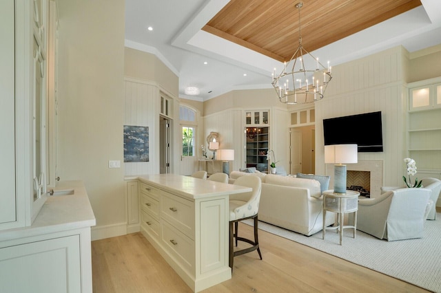 spacious closet featuring a tray ceiling, a fireplace, light wood-style flooring, and a notable chandelier