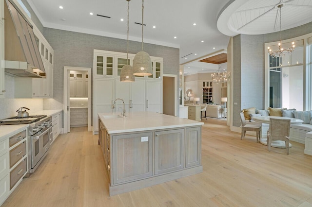 kitchen featuring range with two ovens, a large island, an inviting chandelier, ventilation hood, and light wood-type flooring