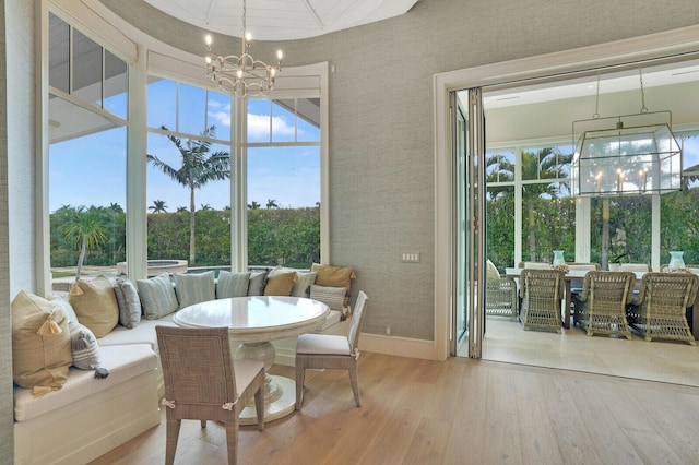 dining space with wood finished floors, a wealth of natural light, and a notable chandelier