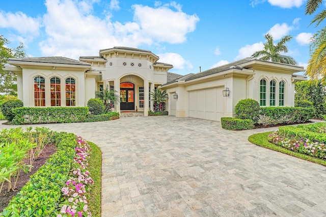 mediterranean / spanish home featuring an attached garage, decorative driveway, and stucco siding