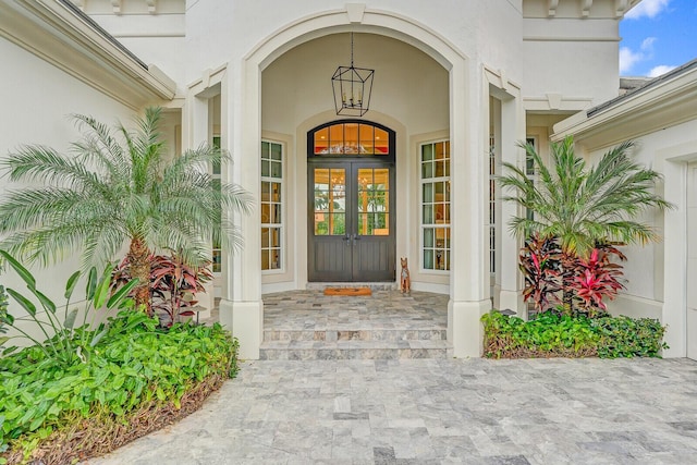 view of exterior entry with stucco siding, covered porch, and french doors