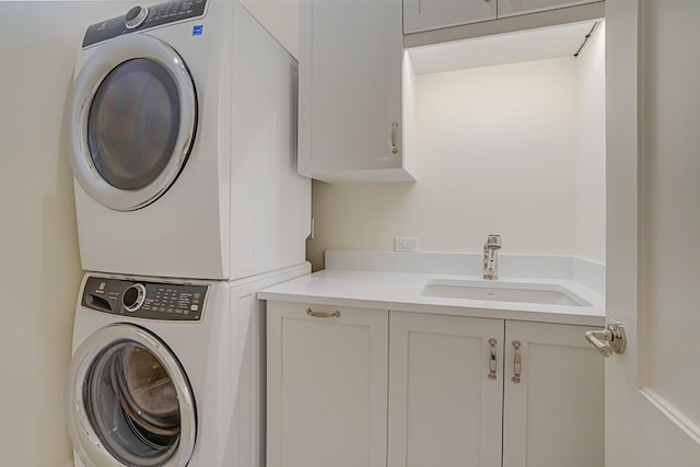 clothes washing area with a sink, cabinet space, and stacked washer / drying machine