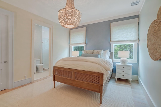 bedroom featuring wood finished floors, connected bathroom, visible vents, and baseboards