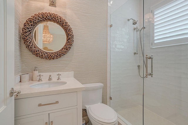 bathroom with toilet, tiled shower, and vanity