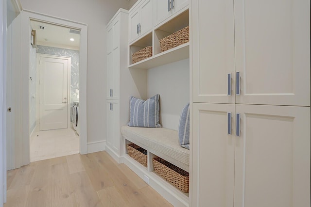 mudroom featuring light wood-type flooring, washer / dryer, and baseboards