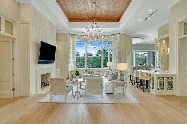 living area featuring light wood-type flooring, wood ceiling, a fireplace, and a raised ceiling