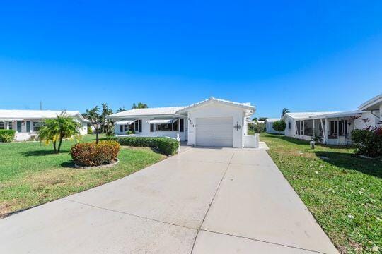 single story home with a front lawn, an attached garage, and driveway