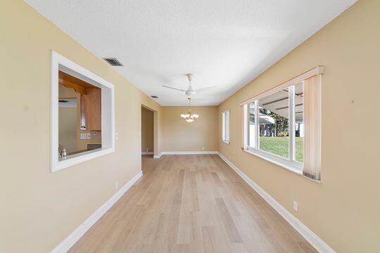 interior space featuring wood finished floors, baseboards, visible vents, a textured ceiling, and a chandelier