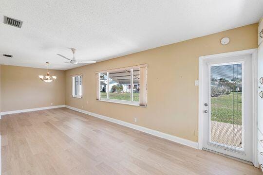 unfurnished room with visible vents, a textured ceiling, light wood-type flooring, and baseboards