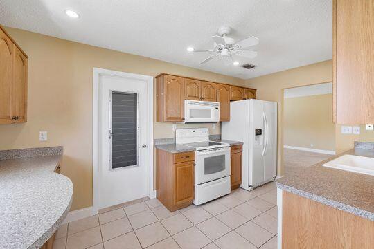 kitchen featuring white appliances, light tile patterned flooring, recessed lighting, a sink, and ceiling fan