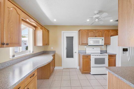 kitchen featuring white appliances, light tile patterned flooring, light countertops, and ceiling fan