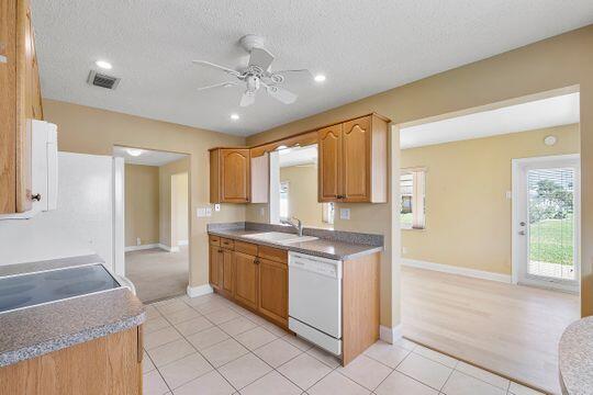 kitchen with visible vents, light tile patterned floors, white dishwasher, a textured ceiling, and a ceiling fan