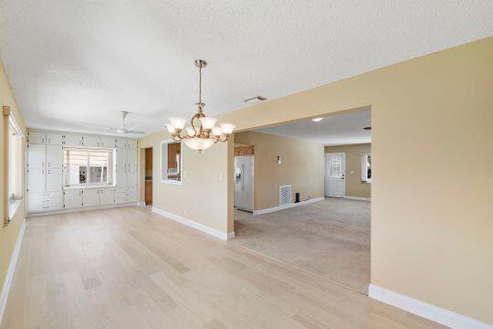 unfurnished room with light wood-style floors, baseboards, and a textured ceiling