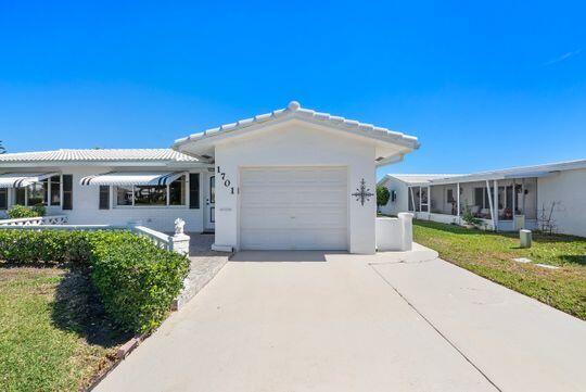 view of front of house featuring a garage, a front lawn, driveway, and stucco siding