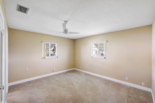 unfurnished room with visible vents, carpet flooring, a ceiling fan, and baseboards