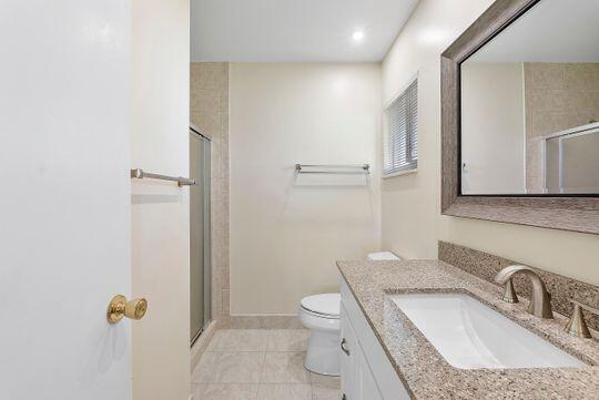 bathroom featuring vanity, toilet, a stall shower, and tile patterned flooring