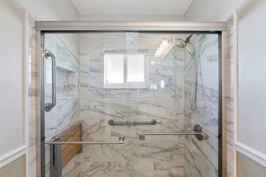 full bathroom featuring a marble finish shower