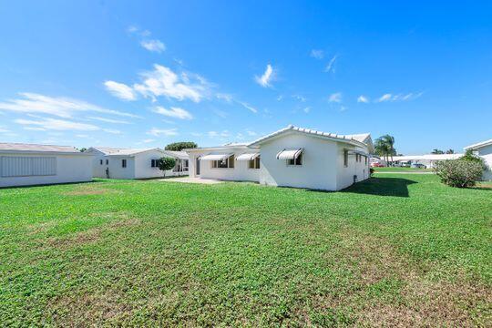 back of house featuring stucco siding and a lawn