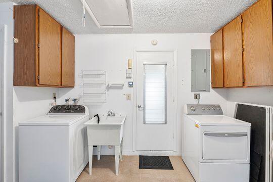 washroom featuring electric panel, cabinet space, a textured ceiling, and washing machine and dryer