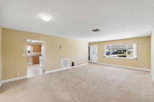 unfurnished living room featuring light carpet, baseboards, visible vents, and a textured ceiling