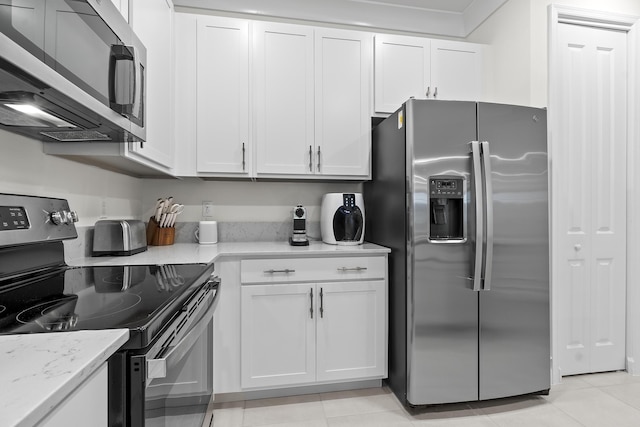 kitchen featuring light tile patterned floors, appliances with stainless steel finishes, light stone counters, and white cabinets