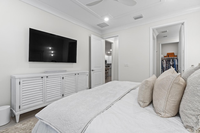 bedroom with ceiling fan, wood finished floors, visible vents, and a walk in closet