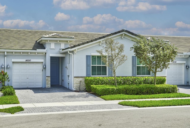 view of front of house with decorative driveway, stone siding, a tile roof, and stucco siding