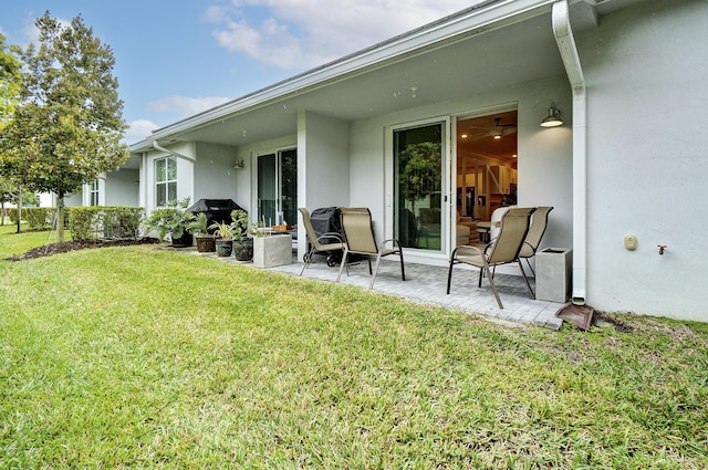 rear view of house featuring a patio, a lawn, and stucco siding