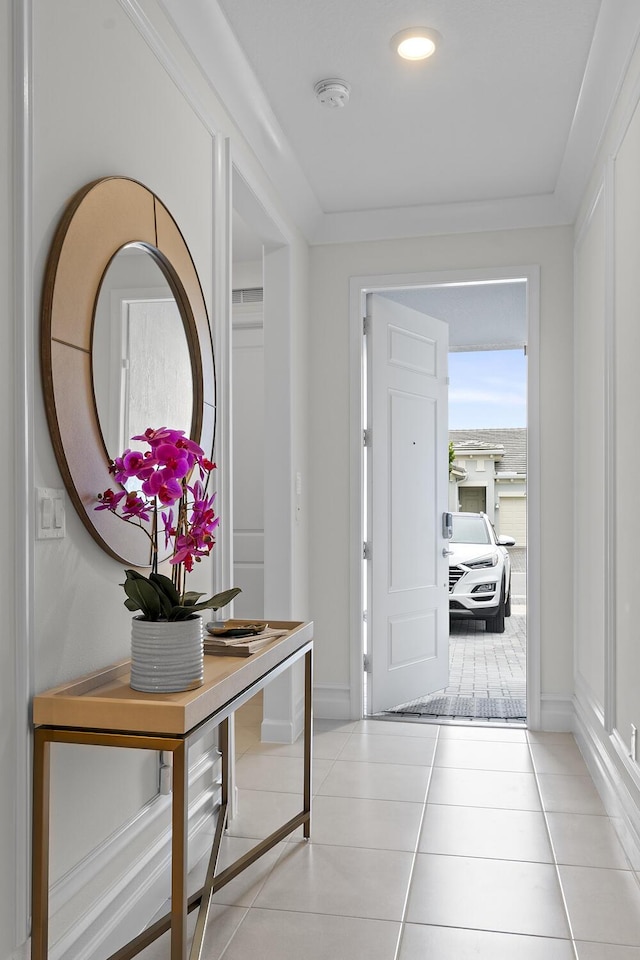 foyer featuring crown molding, baseboards, and tile patterned floors