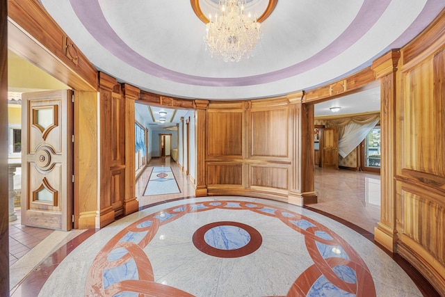 bedroom with wooden walls, marble finish floor, a tray ceiling, a decorative wall, and a notable chandelier