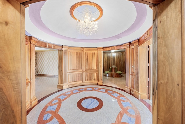 unfurnished bedroom with wallpapered walls, a raised ceiling, and an inviting chandelier