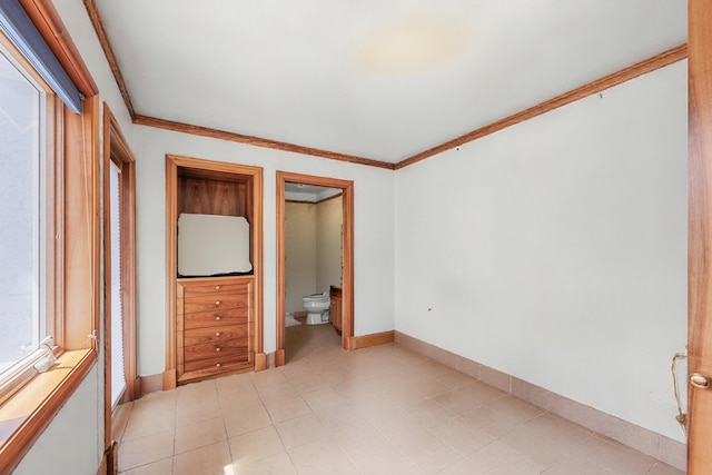 unfurnished bedroom featuring ensuite bath, baseboards, and crown molding