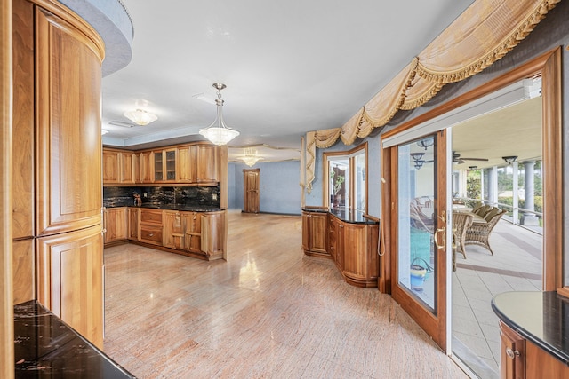 kitchen featuring glass insert cabinets, brown cabinets, backsplash, and decorative light fixtures