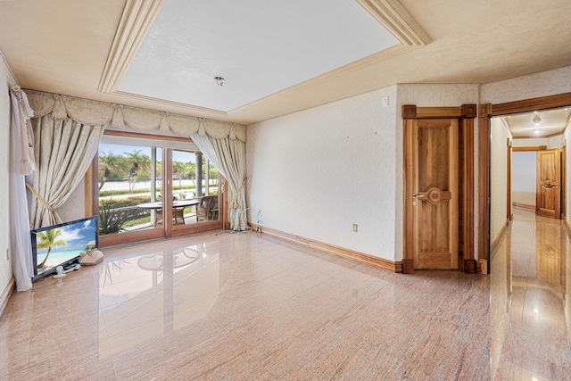 empty room featuring crown molding, a raised ceiling, and baseboards