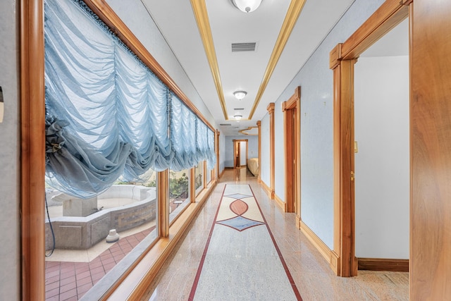 hall with baseboards, visible vents, and light speckled floor