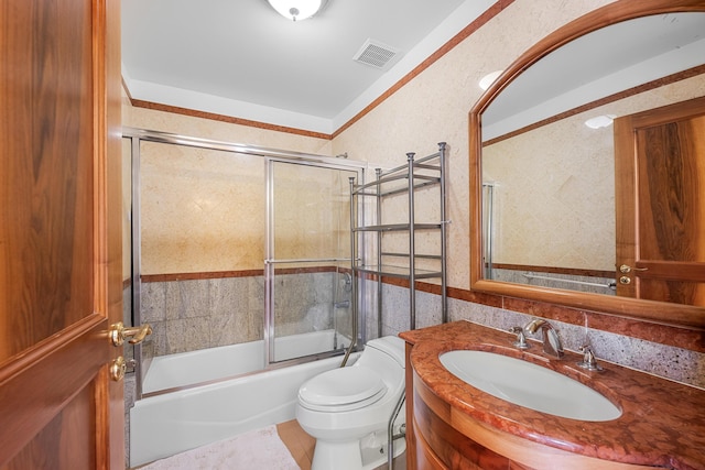 bathroom featuring toilet, shower / bath combination with glass door, vanity, visible vents, and wainscoting