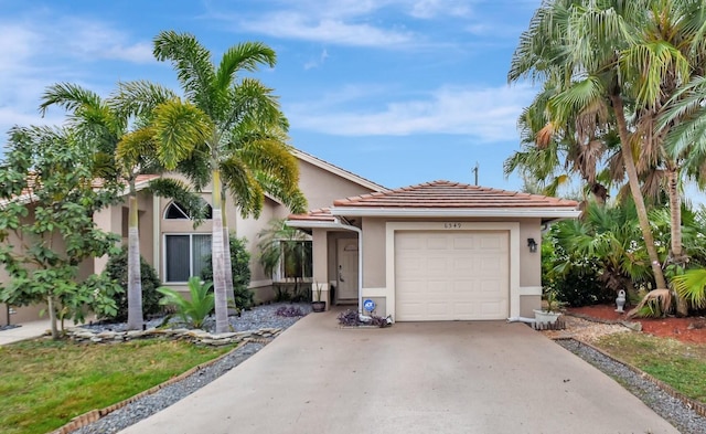 view of front facade featuring stucco siding, driveway, a tile roof, and a garage