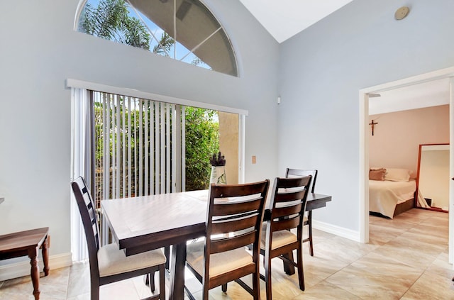 dining area featuring baseboards and a towering ceiling