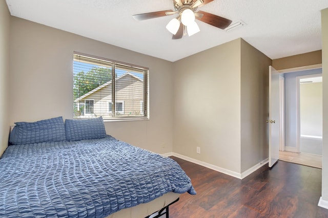 bedroom with a textured ceiling, wood finished floors, baseboards, and ceiling fan