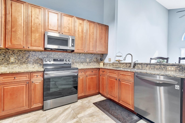 kitchen with light stone countertops, tasteful backsplash, appliances with stainless steel finishes, and a sink