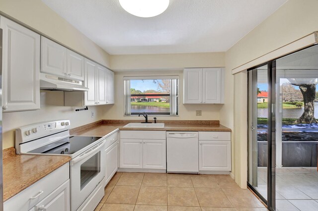 kitchen with white appliances, a sink, white cabinetry, and under cabinet range hood