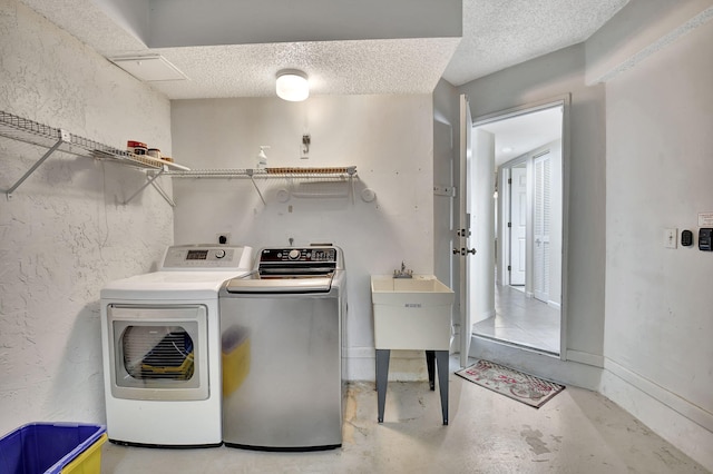 clothes washing area featuring laundry area, a textured ceiling, baseboards, and washer and dryer