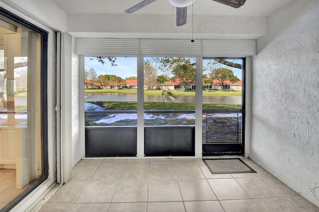 unfurnished sunroom with a water view, a healthy amount of sunlight, and a ceiling fan