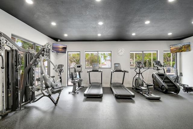 workout area featuring a textured ceiling, baseboards, and recessed lighting