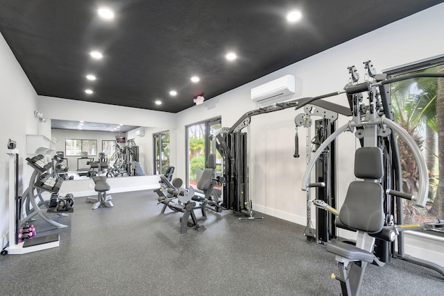 gym with a healthy amount of sunlight, a wall mounted AC, recessed lighting, and baseboards