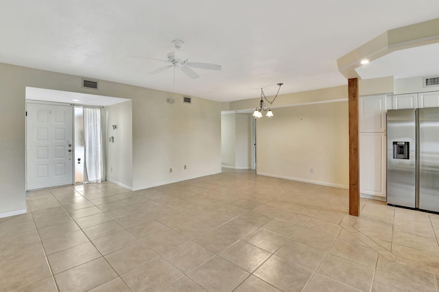 interior space featuring light tile patterned floors, baseboards, visible vents, and ceiling fan with notable chandelier